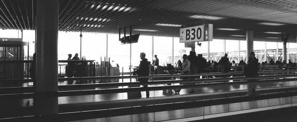 black-and-white-photo-of-people-sitting-and-standing-at-airport-gate-B30