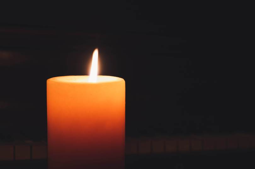 A yellow/orange candle burning in darkness