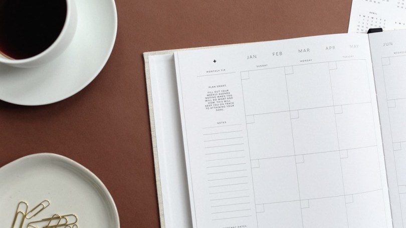 yearly calendar on table with cup of coffee and dish of paper clips