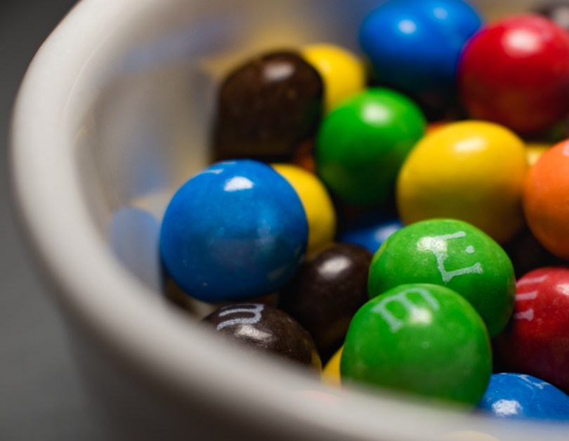 Colorful peanut M&M candies in a white ceramic bowl.
