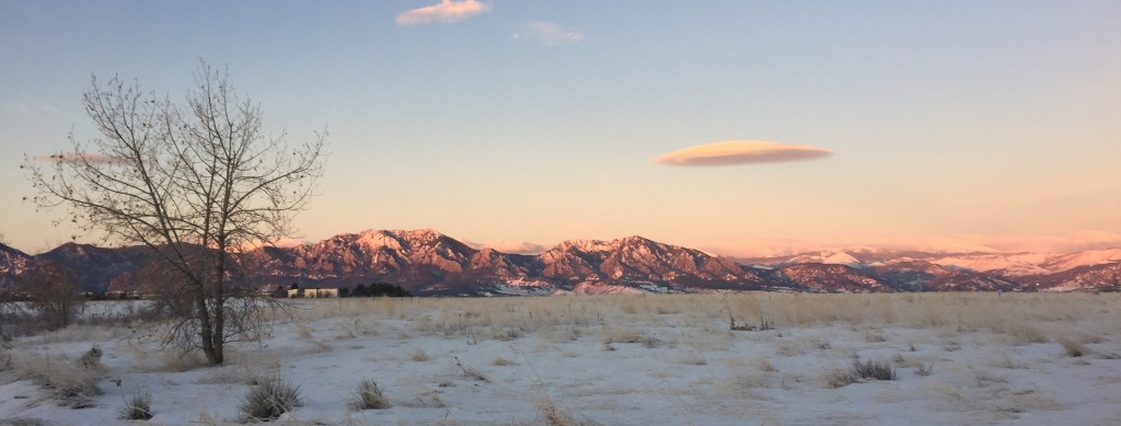 blue and pink mountains illuminated by sunrise over snowy plains