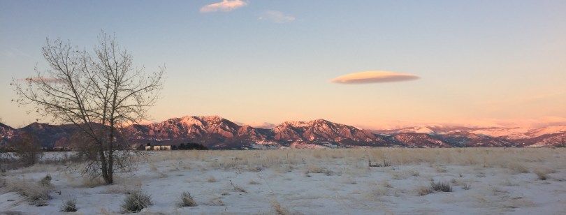 blue and pink mountains illuminated by sunrise over snowy plains