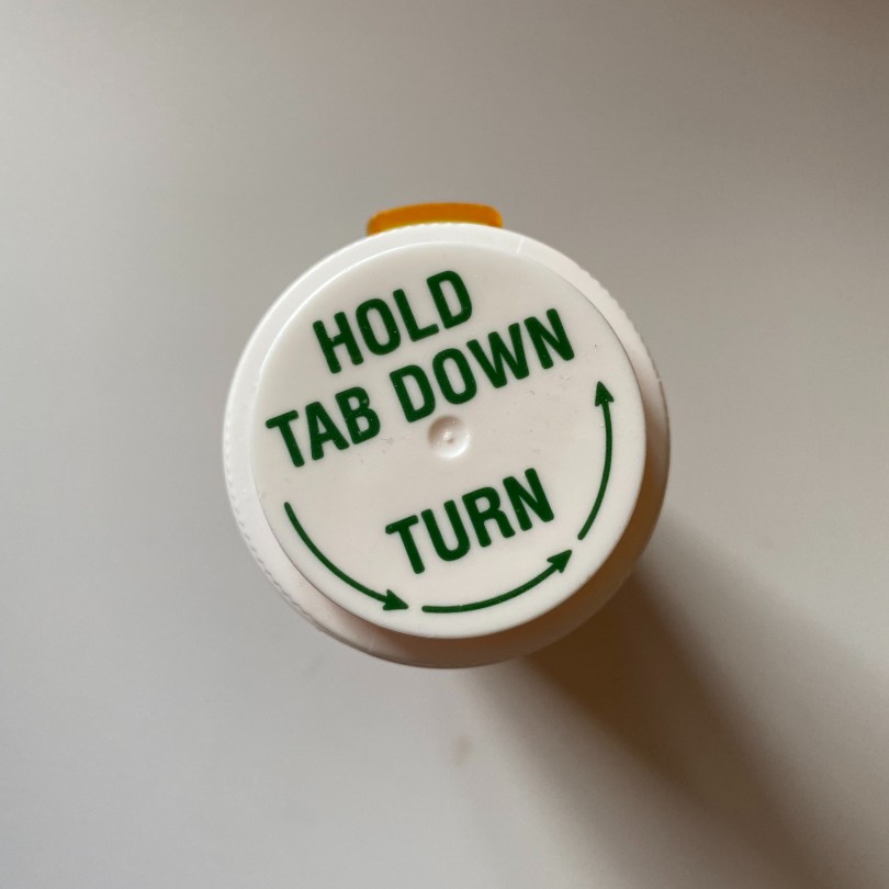 top-down-view-of-pill-bottle-with-tex-hold-tab-down-turn-with-arrows