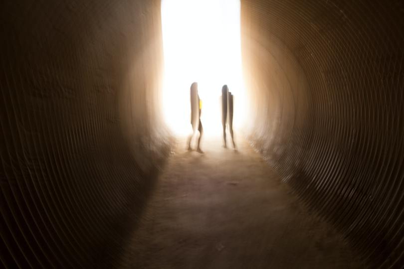 blurry-photo-of-two-people-standing-in-dark-tunnel-with-beam-of-light