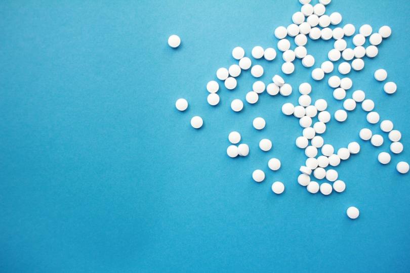 scattered-white-pills-in-upper-right-quadrant-on-light-blue-background
