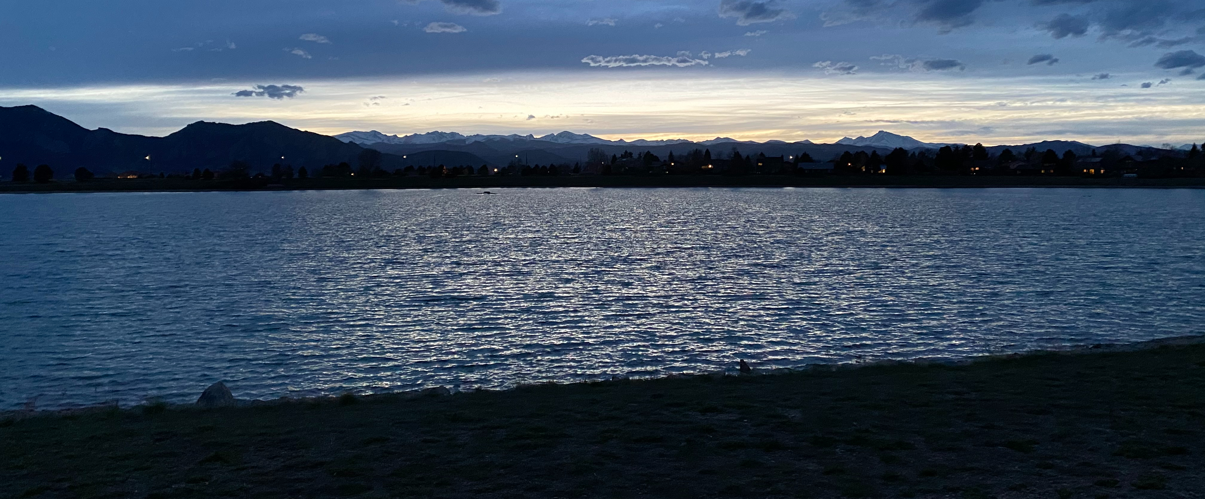 A blue lake with mountains in the background and a dark sky at night