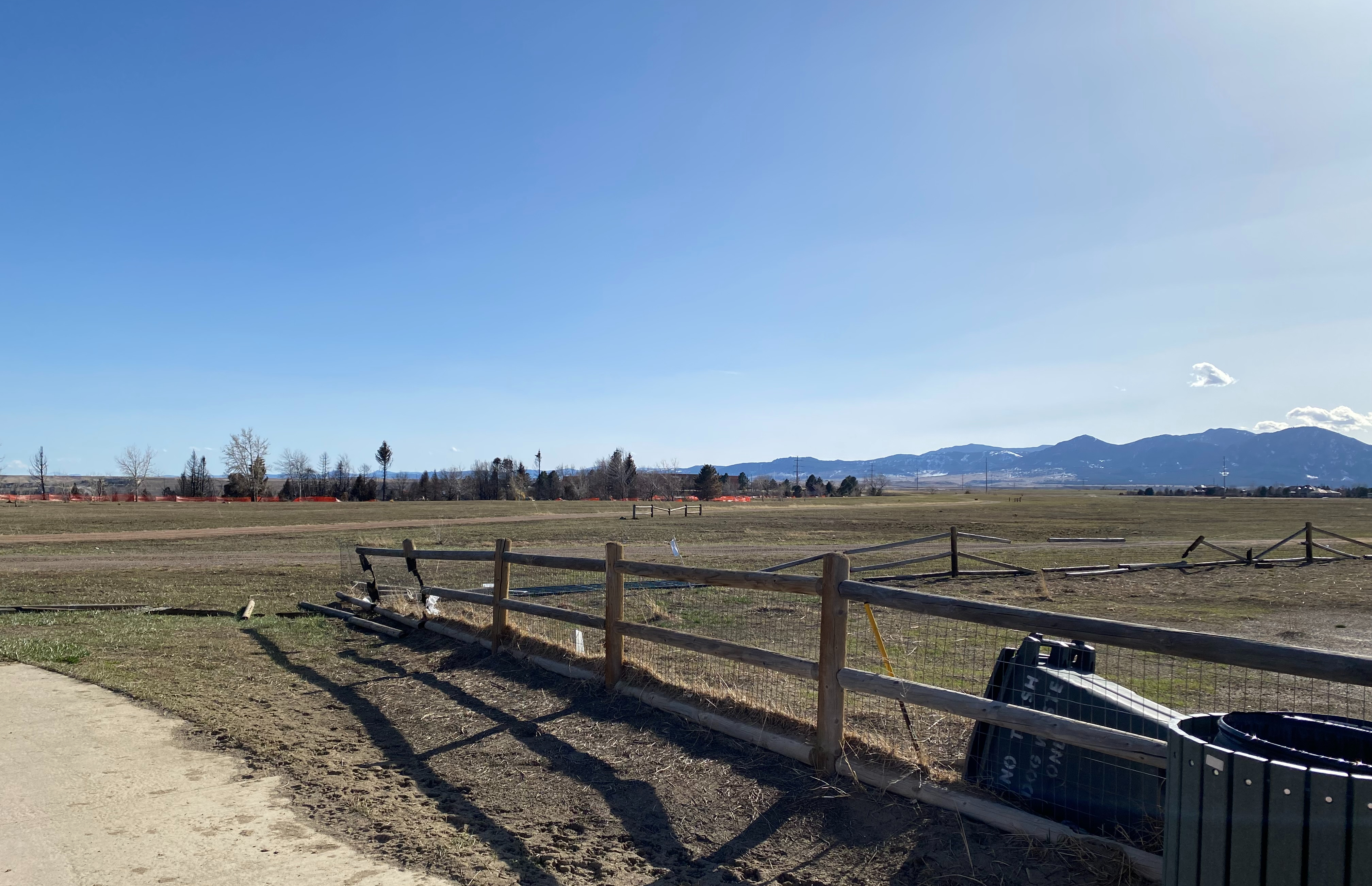 A flat landscape with mountains in the background and partially destroyed wooden fences in the foreground