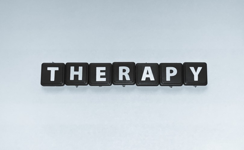 Black tiles with white letters spelling therapy on a blank background